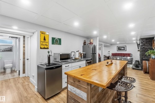 Entertainment area featuring a rustic wood-finish bar with seating, recessed lighting, and wood-finish flooring - 11431 144 Avenue, Edmonton, AB 