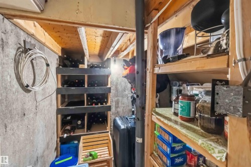 Concrete foundation walls featuring exposed wood joists and built-in wood shelving - 11431 144 Avenue, Edmonton, AB 