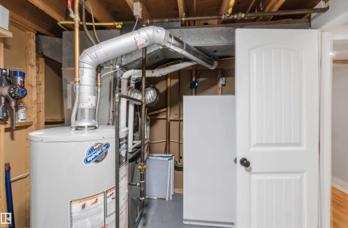 Mechanical room featuring a water heater, exposed ceiling joists, and visible utility lines - 11431 144 Avenue, Edmonton, AB 