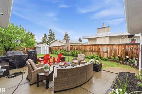 Expansive concrete patio with multiple seating areas, offering direct access to a manicured lawn - 11431 144 Avenue, Edmonton, AB 