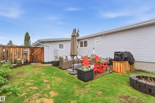 Expansive concrete patio area with a privacy fence, block fire pit, and a grassy yard - 11431 144 Avenue, Edmonton, AB 
