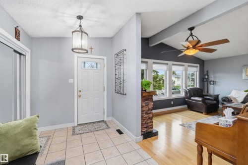 Entryway featuring tile flooring, a lantern-style pendant light, and a white front door with decorative glass - 11431 144 Avenue, Edmonton, AB 