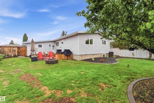 Expansive backyard featuring a manicured lawn, a built-in fire pit, and a wooden deck - 11431 144 Avenue, Edmonton, AB 