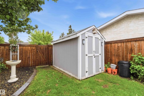 Backyard featuring a grey storage shed with white double doors, bordered by a wood privacy fence - 11431 144 Avenue, Edmonton, AB 