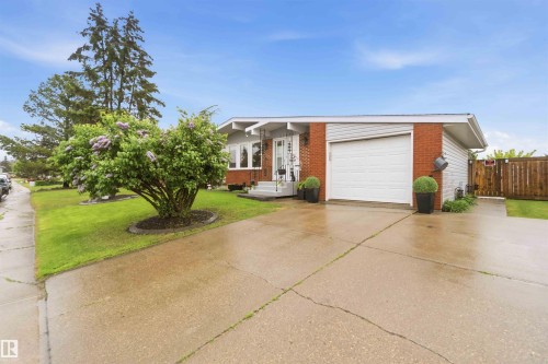 Ranch-style exterior featuring a red brick facade with white siding accents and a white garage door - 11431 144 Avenue, Edmonton, AB 