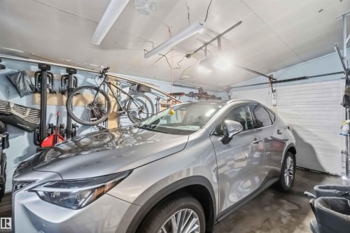 Attached garage featuring a concrete floor, light blue wall paint, and white paneled garage door - 11431 144 Avenue, Edmonton, AB 