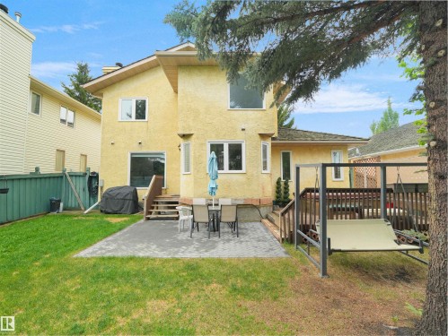 Expansive backyard featuring a manicured lawn, a large patio area with paver stones, and a wooden deck with railing - 208 Ferguson Place, Edmonton, AB 