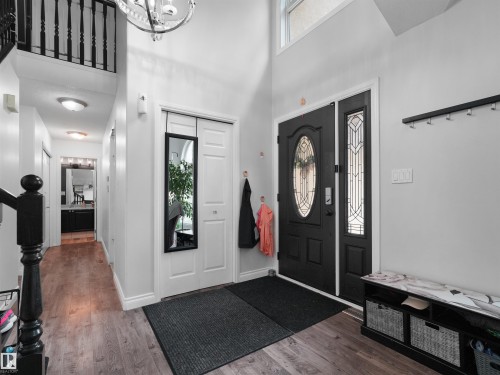 Entryway featuring a decorative black front door with side panel, high ceilings, and wood-finish flooring - 208 Ferguson Place, Edmonton, AB 