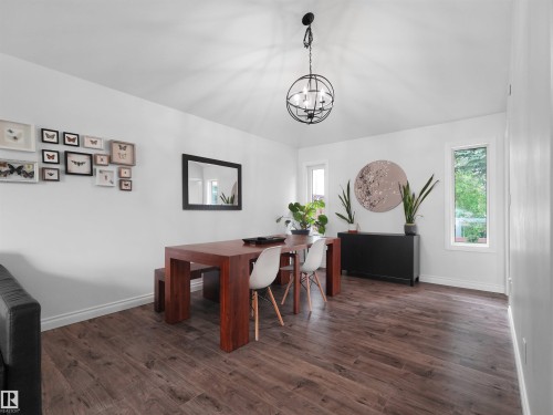 Dining area featuring wood-finish flooring, white baseboards, and a contemporary spherical chandelier - 208 Ferguson Place, Edmonton, AB 