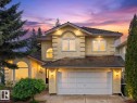 Stucco exterior featuring arched and rectangular windows, a shingled roof, an attached two-car garage, and multiple exterior lighting fixtures - 208 Ferguson Place, Edmonton, AB 