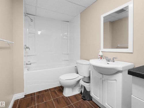 Bathroom featuring a white bathtub with shower, white toilet, and a white vanity with a ceramic basin - 208 Ferguson Place, Edmonton, AB 