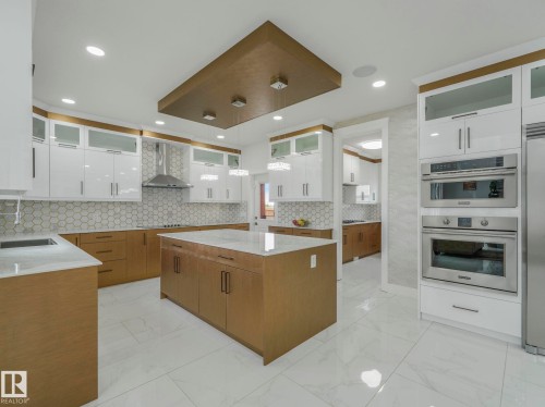 Modern kitchen featuring white-finish and wood-finish cabinetry with a contrasting island - 3101 Pelerin Crescent, Beaumont, AB 