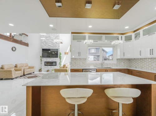 Kitchen island with a white polished countertop and natural wood-finish base - 3101 Pelerin Crescent, Beaumont, AB 
