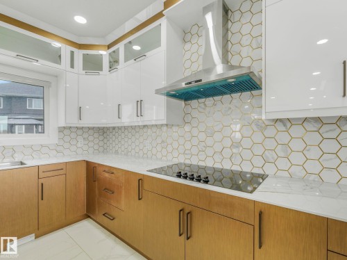 Modern kitchen with two-tone cabinetry featuring white upper cabinets and natural wood-finish lower cabinets - 3101 Pelerin Crescent, Beaumont, AB 