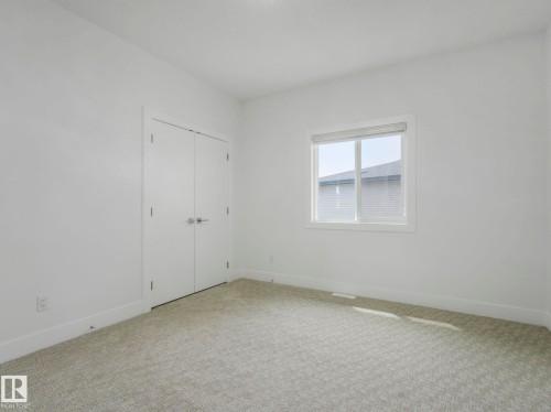 Bright interior space featuring light-colored patterned carpeting, white walls, and white baseboards - 3101 Pelerin Crescent, Beaumont, AB 