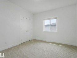 Bright interior space featuring light-colored patterned carpeting, white walls, and white baseboards - 