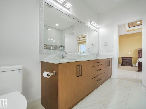Dual-sink vanity with wood-finish cabinetry, a light-toned countertop, and modern hardware - 3101 Pelerin Crescent, Beaumont, AB 