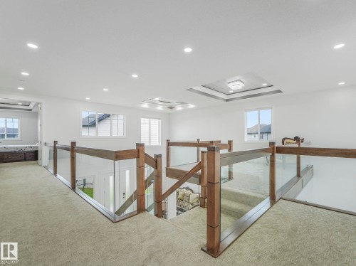 Stairwell featuring glass panel railings with wood newel posts and handrails - 3101 Pelerin Crescent, Beaumont, AB 