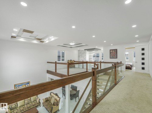 Upper-level landing featuring wood-finish and glass railings, recessed lighting, and a textured carpeted floor - 3101 Pelerin Crescent, Beaumont, AB 