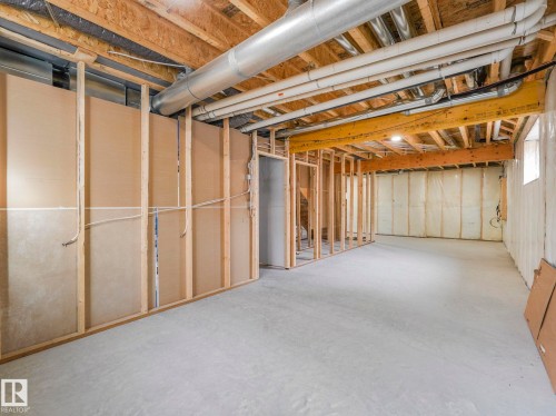 Unfinished basement with concrete flooring, exposed wooden joists, and visible utility conduits - 3101 Pelerin Crescent, Beaumont, AB 
