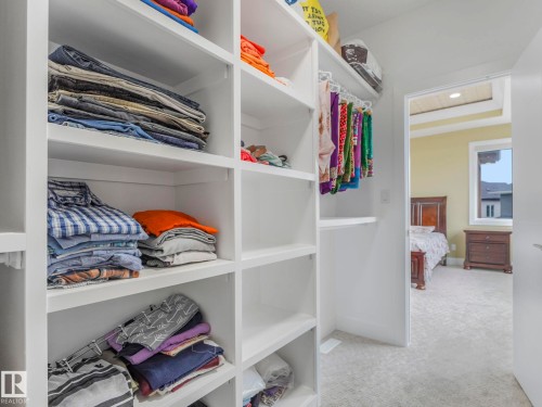Custom closet system with white shelving and integrated hanging rods - 3101 Pelerin Crescent, Beaumont, AB 