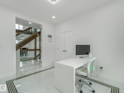 Light-filled room featuring polished tile flooring with a decorative border, recessed lighting, and a modern chandelier - 