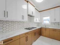 Contemporary kitchen featuring two-tone cabinetry with white upper cabinets and natural wood-finish lower cabinets, complemented by dark hardware - 