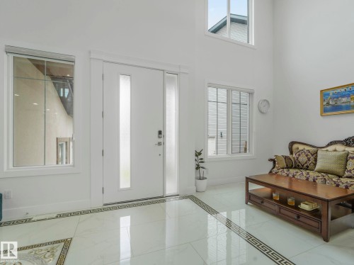 Two-story entryway featuring a white entry door with frosted glass panels, an adjacent frosted sidelight, and an overhead transom window - 3101 Pelerin Crescent, Beaumont, AB 