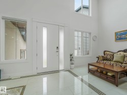 Two-story entryway featuring a white entry door with frosted glass panels, an adjacent frosted sidelight, and an overhead transom window - 
