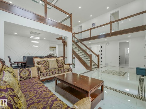 Bright interior with polished tile flooring, a prominent staircase with wood and glass railings, and a second-story open walkway - 3101 Pelerin Crescent, Beaumont, AB 
