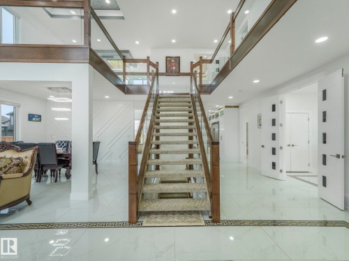 Grand foyer featuring a central staircase with wood-finish handrails and glass panels - 3101 Pelerin Crescent, Beaumont, AB 