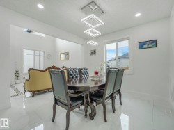 Open-concept dining area featuring a modern rectangular chandelier, recessed lighting, and large windows - 