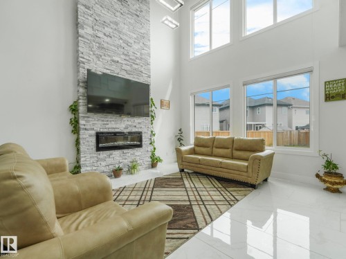 Living space featuring a full-height stone-clad fireplace with an integrated linear electric fireplace - 3101 Pelerin Crescent, Beaumont, AB 