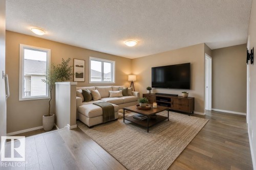 Open-concept living area featuring light-toned wood-finish flooring and neutral wall tones.Virtually Staged Photos - 2031 207 Street, Edmonton, AB 