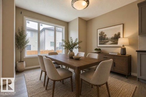 Spacious dining area featuring wood-finish flooring, a large window, neutral wall tones, a built-in sideboard, and an overhead fixture - 2031 207 Street, Edmonton, AB 