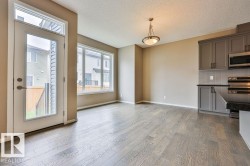 Open-concept living space featuring wood-finish flooring, a full-light exterior door, and a multi-pane window - 
