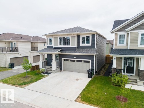 Contemporary two-story residence with a two-car garage, featuring a mixed material facade of dark gray siding and lighter accent panels - 2031 207 Street, Edmonton, AB 