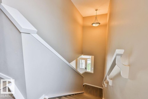 Staircase with light wood-finish treads, white risers, and a contemporary white handrail - 2031 207 Street, Edmonton, AB 