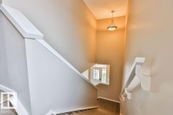 Staircase with light wood-finish treads, white risers, and a contemporary white handrail - 