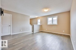 Spacious room featuring light wood-finish flooring, neutral wall paint, white trim, and multiple windows - 