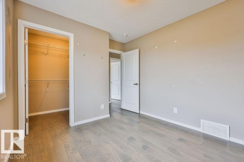 Room featuring wood-finish flooring, neutral wall paint, and a built-in closet with shelving - 2031 207 Street, Edmonton, AB 