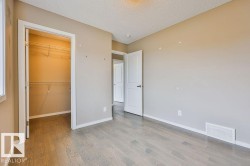 Room featuring wood-finish flooring, neutral wall paint, and a built-in closet with shelving - 