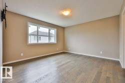 Spacious room featuring wood-finish flooring, neutral wall paint, and a large window - 