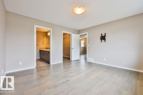 Spacious room featuring wood-finish flooring, neutral wall tones, and recessed lighting - 2031 207 Street, Edmonton, AB 