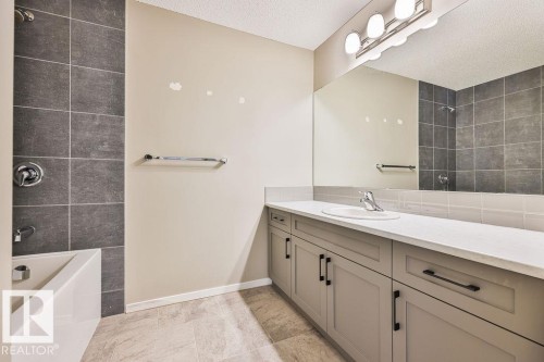 Bathroom featuring a spacious vanity with an integrated sink, light-colored countertop, and ample storage cabinetry - 2031 207 Street, Edmonton, AB 