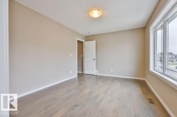 Spacious room featuring light-toned walls, wood-finish flooring, and a large multi-pane window - 