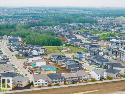 Aerial perspective showcasing a developed residential community with a mix of single-family homes and townhomes, featuring a central park area with mature trees - 2031 207 Street, Edmonton, AB 