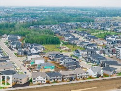Aerial perspective showcasing a developed residential community with a mix of single-family homes and townhomes, featuring a central park area with mature trees - 