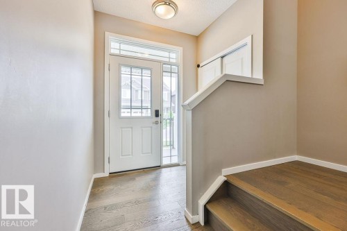 Entryway featuring a white door with decorative glass inserts, a coordinating sidelight, and an overhead transom window - 2031 207 Street, Edmonton, AB 