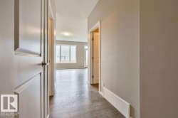 Hallway featuring rich wood-finish flooring, light neutral wall tones, and recessed baseboard heating - 